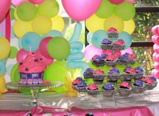 lindo bolo cupcake com balões amarelo azul e rosa ao fundo