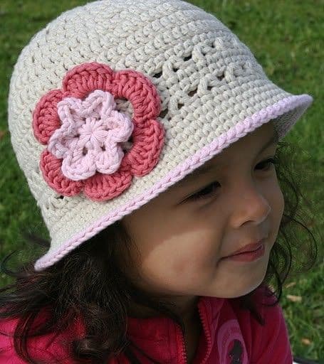 menina com chapéu de crochê na cor cru com aplique de rosa em dois tons rosados