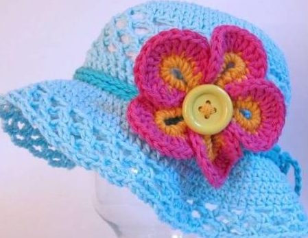 chapéu azul com cordão em crochê e aplique de flor com botão no centro representando o miolo