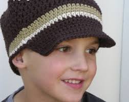 garoto com boné de crochê na cor marrom com detalhe no crochê nas cores bege e braco