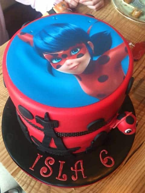 Imagem da Ladybug com fundo azul no topo do bolo vermelho.