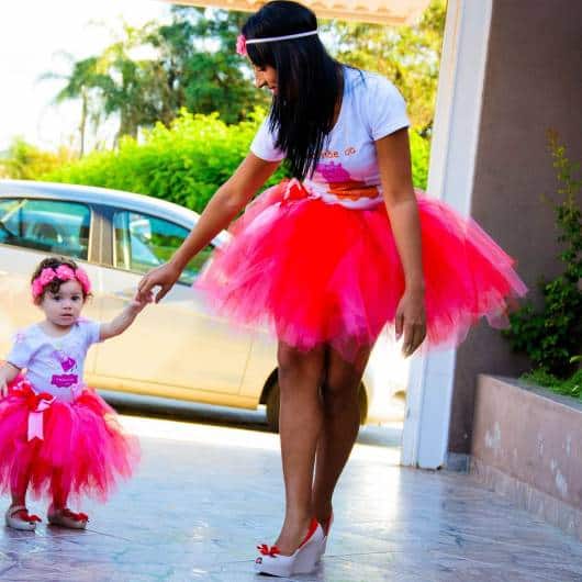 Mãe e filha usando saia de tule rosa choque e camiseta branca.