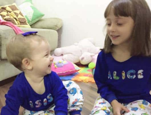 Menina e irmã bebê vestindo o mesmo pijama personalizado.
