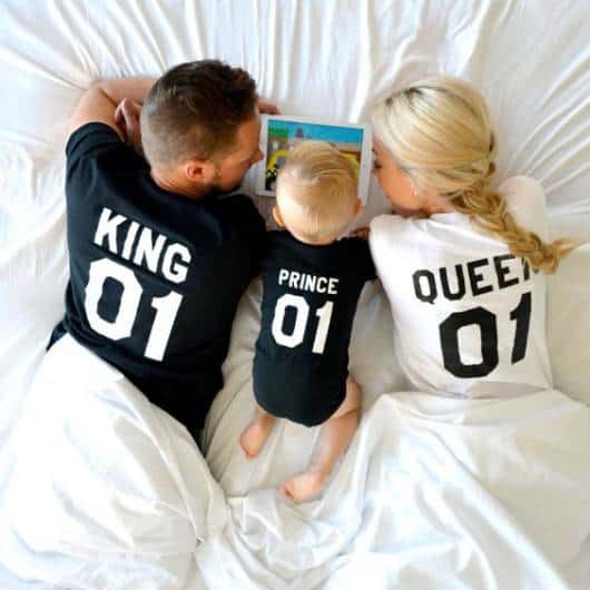 Mãe, pai e filho usando pijamas escrito "King, Prince, Queen".