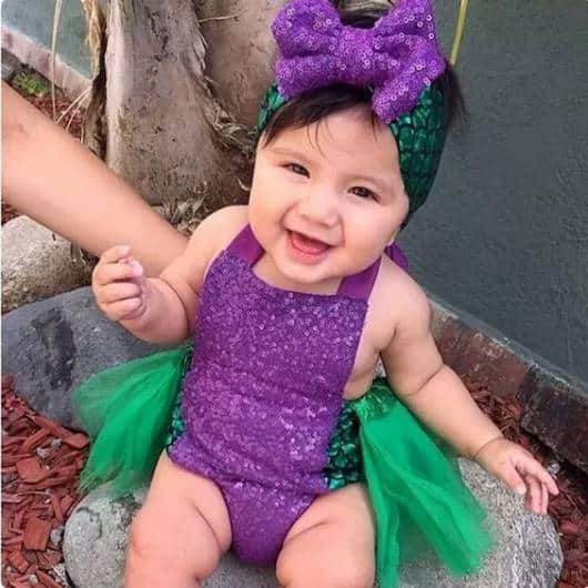 Bebê usando fantasia Ariel, com body roxo e saia verde.