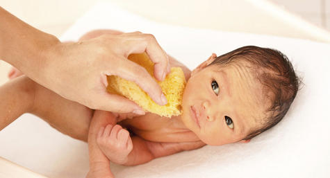 bebê tomando banho com esponja