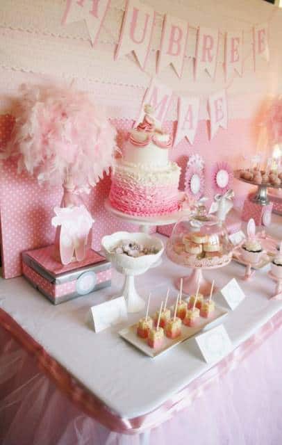 a-table-topped-with-lots-of-pink-desserts-and-cupcakes-on-top-of-plates