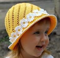menina loira com chapeu de croche na cor amarela com faixa de rosas brancas