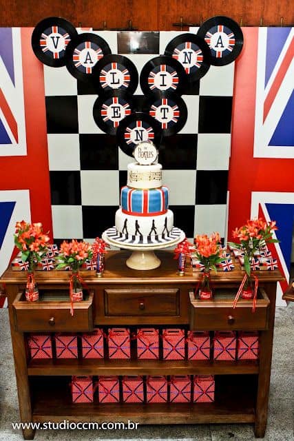 Festa Rock n' Roll com bandeira da Inglaterra no fundo da mesa do bolo.