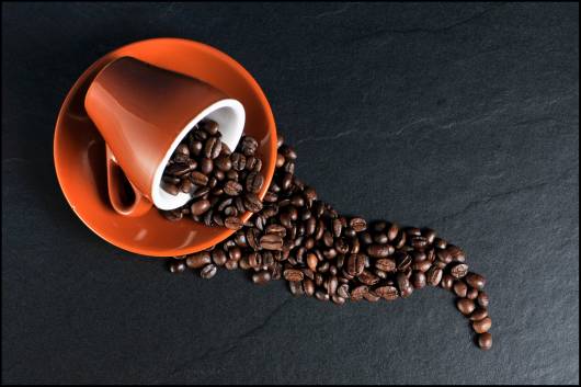 Xícara de café caída com grão de café.