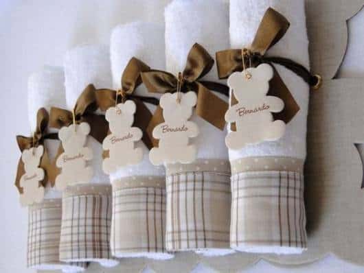 Rolinhos de toalhas com borda xadrez presas com lacinho marrom.