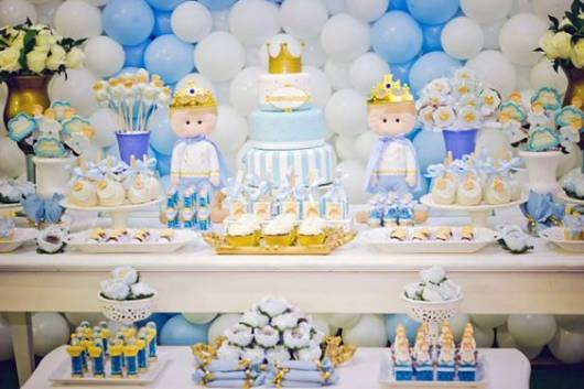 Imagem de mesa de bolo decorada com itens brancos e azuis.