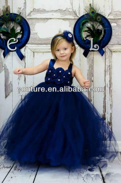 Bebê usa vestido azul marinho longo de alcinha, com detalhes em pérolas.