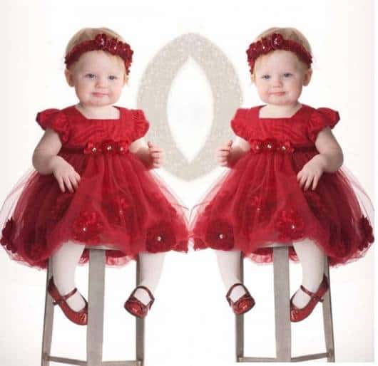 Bebê veste vestido vermelho escuro, meia branca, sapatinho e tiara na mesma cor.