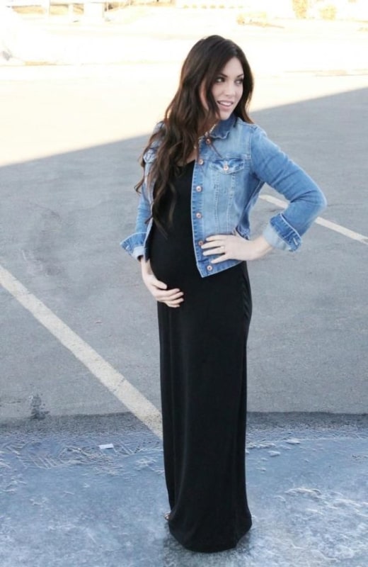 gravida com vestido longo preto e jaqueta jeans